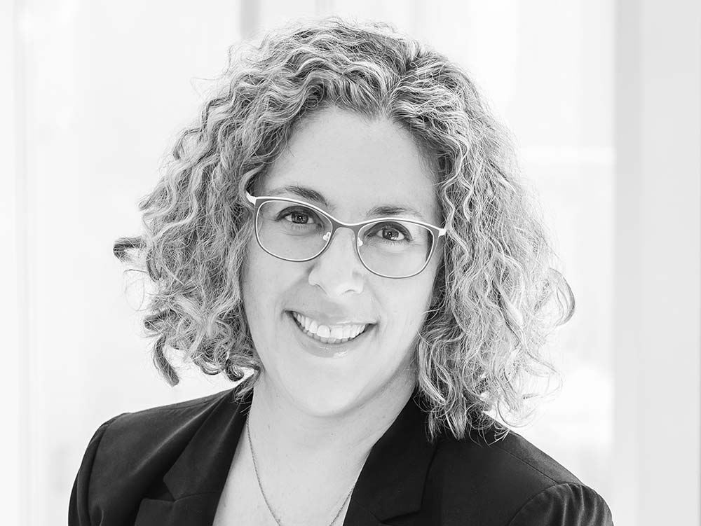 portrait of smiling woman with curly hair and glasses